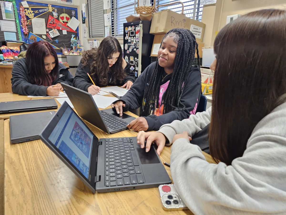 Sabina Mora, Emelly Perlera work on 8th Grade Superlatives while Da'Lonna Pridgett, and Marlyn Osorio design yearbook pages.